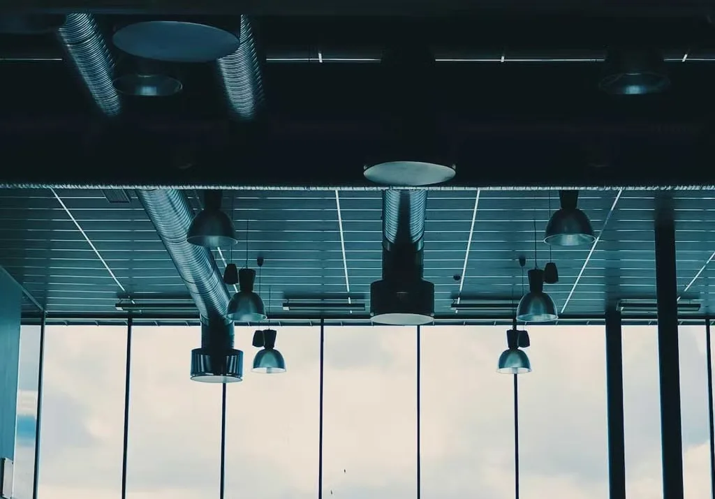 Plafond van een kantoorruimte met ventilatiekanalen en hanglampen